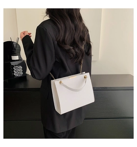 Detailed shot of white crocodile embossed shoulder bag with gold chain strap on model