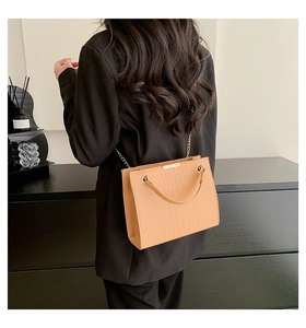 Detail of stone pattern shoulder bag with gold metal trim and chain strap on model