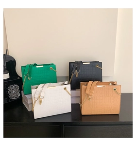 Detailed view of crocodile embossed shoulder bags in green, black, white and camel colors