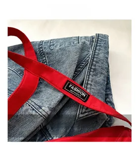 Détail de la bandoulière en nylon rouge avec étiquette FASHION INSTINCT sur denim