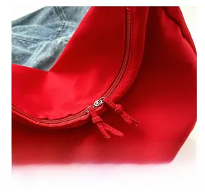 Détail de la fermeture à double glissière fluide sur le sac porté épaule en toile rouge