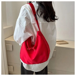 Détail du sac bandoulière rouge en oxford avec lettrage 'FASHION' sur la sangle