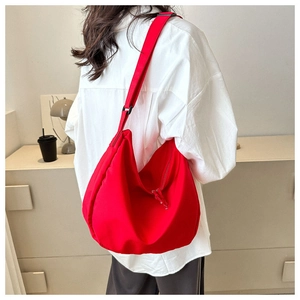Sac à bandoulière croissant en nylon rouge porté par un mannequin au design spacieux