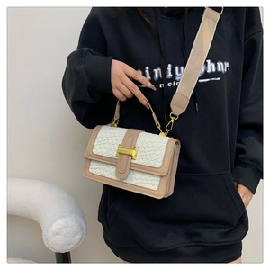 Detail of crossbody bag featuring white woven texture and golden H-shaped buckle