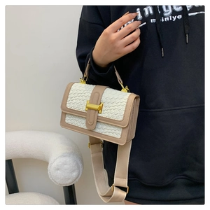 Detail of woven crossbody bag with cream leather trim and gold square metal lock clasp
