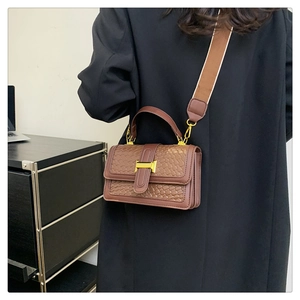 Detailed view of brown woven texture handbag with golden H-shaped metal buckle detail