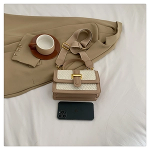 Close-up of beige crossbody bag with woven texture flap and golden square lock detail