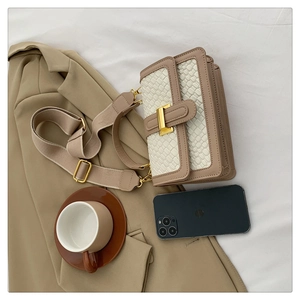 Close-up of woven texture flap and golden buckle on retro khaki crossbody bag