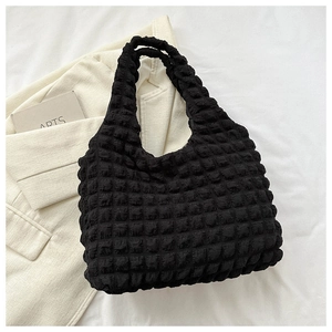 Close-up of black puffy bubble textured fabric hand bag on white minimalist background