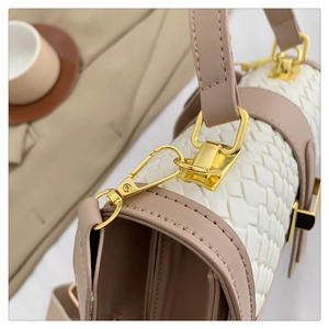 Close-up of white woven leather texture with pink handles and golden metal hardware details