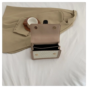 Detail view of beige crossbody bag showing metal magnetic snaps and double compartment interior