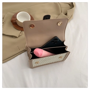 Dual compartments detail of a woven flap bag showing capacity for phone and cosmetics