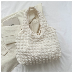 Detail of white puff cloud texture and soft woven fabric on chic minimalist shoulder bag