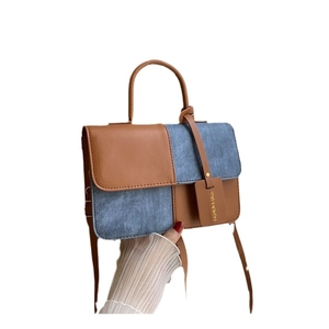 Contrast brown leather and blue denim crossbody bag with top handle and fashion tag