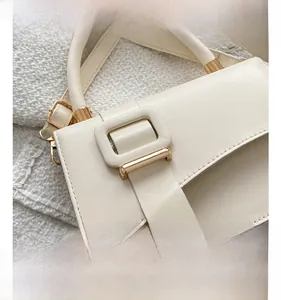 Detail of off-white crossbody bag featuring a large square buckle and gold metal hardware