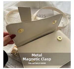 Detail shot of the golden magnetic buckle closure on a minimalist cream shoulder bag