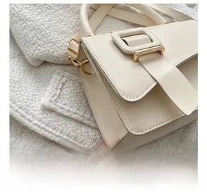 Detail of cream square shoulder bag featuring gold hardware and precise stitching