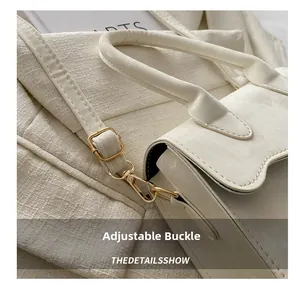Close-up of white leather handbag with adjustable gold buckle and lobster clasp detail