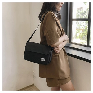 Male model wearing black canvas messenger bag showing large capacity and crossbody strap