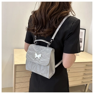Silver-gray backpack detail featuring a butterfly metal clasp and pleated texture fabric
