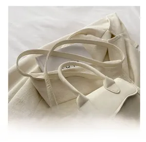 Detail of creamy white leather handbag featuring smooth handle and stitching on blazer
