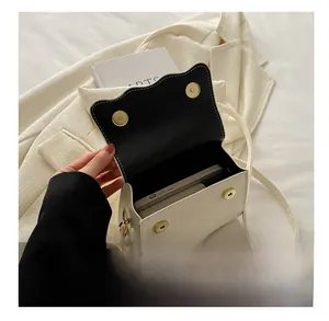 Top view of cream mini crossbody bag showing internal storage for phone and lipstick