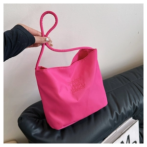 Detail van de neonroze draagtas met reliëfopdruk en een uniek handvat met een knoop