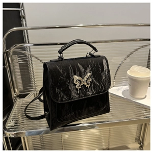 Close-up of black pleated texture faux leather bag with silver butterfly buckle detail