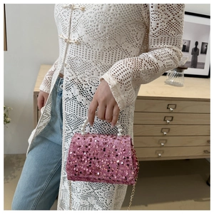 Detailed macro view of pink sequin bag with elegant white pearl handle and gold chain