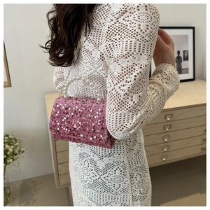 Detail view of pink sequin mini bag featuring pearl handle and gold chain strap