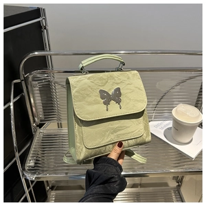 Detail of sage green backpack with wrinkled texture and silver butterfly buckle accent