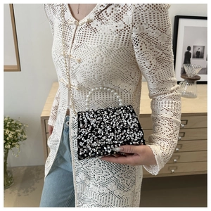 Detail of sequined handbag featuring a luxury pearl handle and gold chain strap