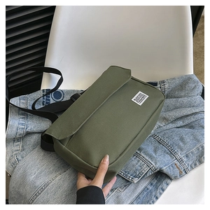 Close-up of military green canvas messenger bag with flap closure and white woven label