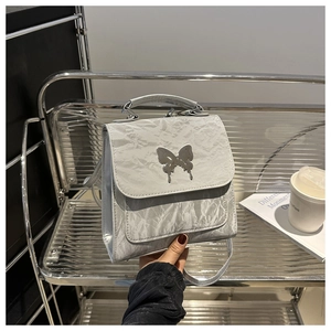 Silver wrinkled PU backpack detail with metallic butterfly logo and silver top handle