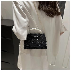 Detail of black sequin handbag with white pearl handle and gold chain strap