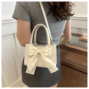 Detail einer cremeweißen Mini-Tasche mit großer Satinschleife und feiner Lederstruktur