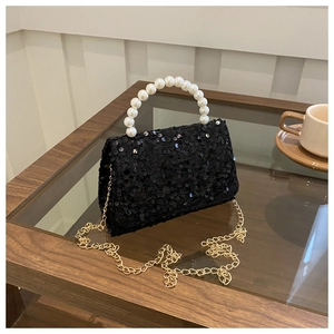 Detail of black sequin handbag featuring white faux pearl handle and gold chain strap
