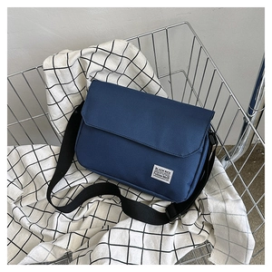 Detail of navy blue canvas messenger bag with adjustable strap and brand label