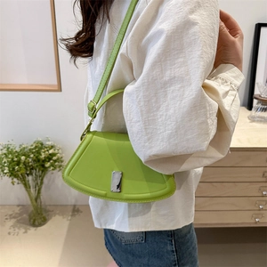 Fruchtgrüne geometrische Ledertasche mit silberner Schnalle, getragen von einem Modell