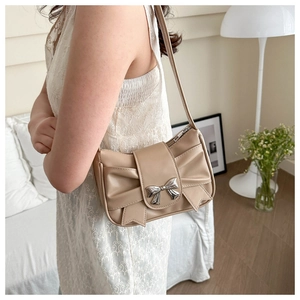 Close-up of beige pleated underarm bag featuring a stylish silver metal bow decoration