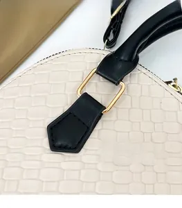 Détail de la boucle dorée et des coutures sur un sac à main tissé avec poignée noire