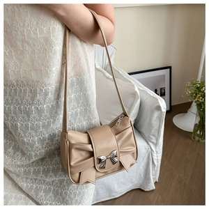 Close-up of the elegant bow detail and metallic buckle on a beige faux leather handbag