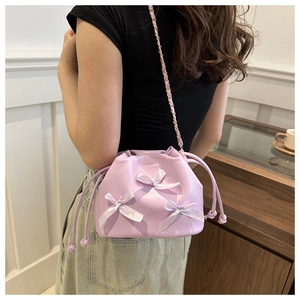 Détail du sac seau lilas à cordon avec nœuds en satin et bandoulière dorée