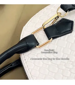 Détail de la boucle en métal doré reliant la poignée noire au sac blanc à texture tressée
