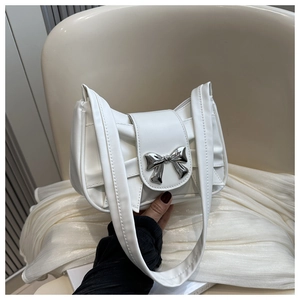 Detail of white pleated shoulder bag featuring a polished silver metal bow ornament