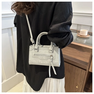 Détail du mini sac à bandoulière gris avec fermeture éclair et franges élégantes