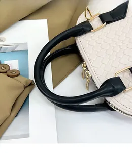 Détail du sac tressé blanc avec poignées en cuir noir et anneaux en D en métal doré