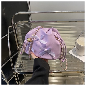 Détail du sac seau lilas orné de nœuds en soie et d'une bandoulière en chaîne métal