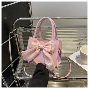 Pink square handbag featuring a large organza bow and top handle shown in lifestyle setting