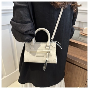 Détail du mini sac à main ivoire avec fermetures éclair décoratives et pompons chic